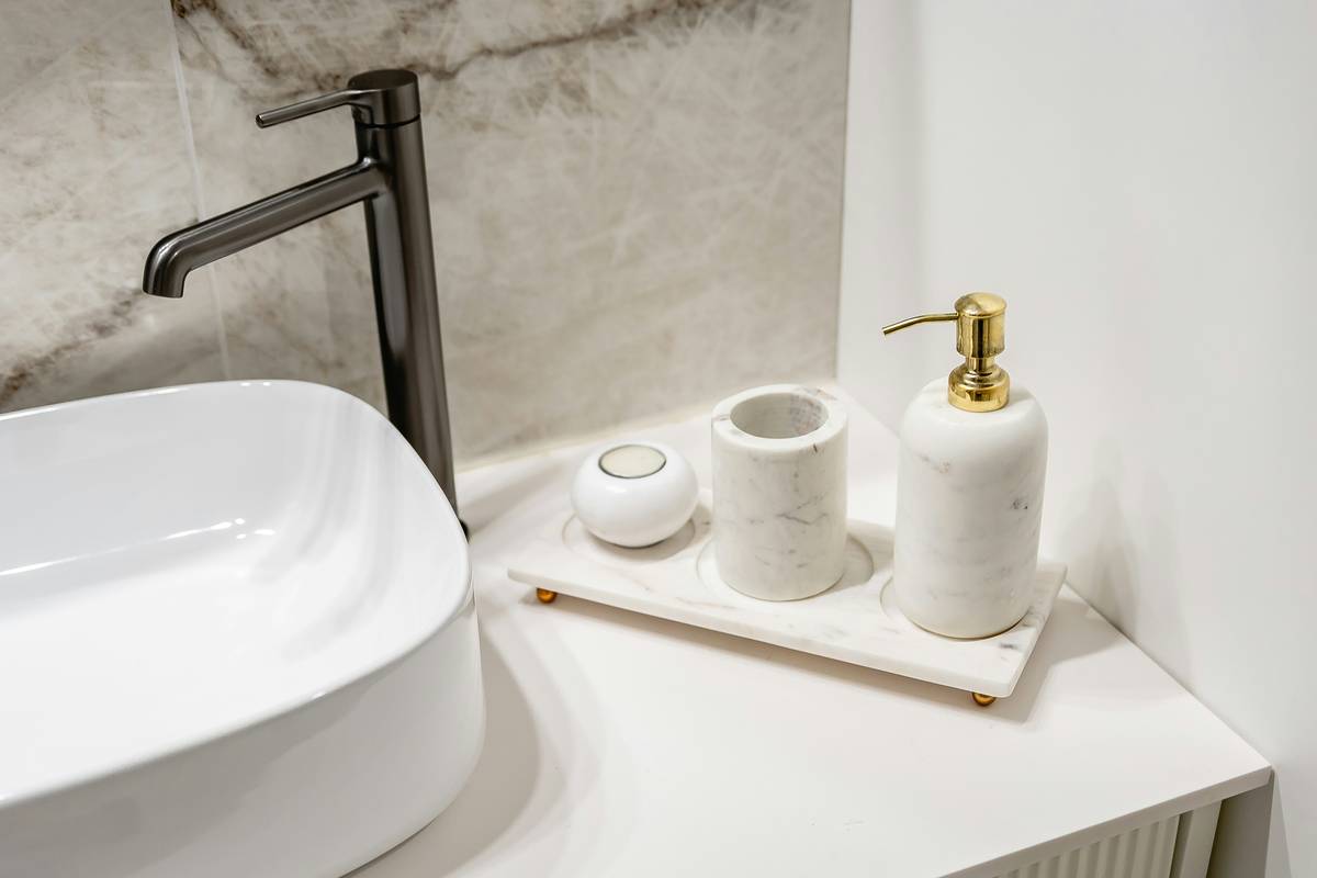 spa bathtub accessories arranged beside a vintage-style clawfoot bathtub: bamboo tray, waterproof Bluetooth speaker, silicone non-slip mat, cedar bath caddy, and chrome overflow cover